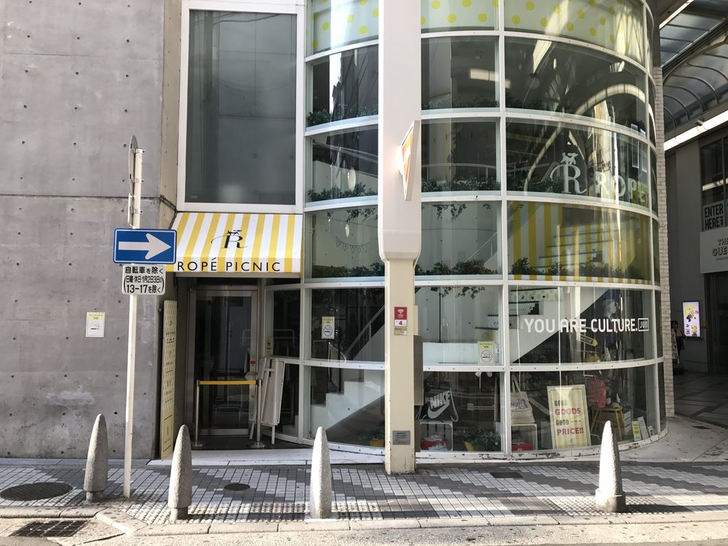 心斎橋TOの曲面ガラスと打放しコンクリートが接する正面外観 / Front view of Shinsaibashi TO where the curved glass facade meets the exposed-concrete wall