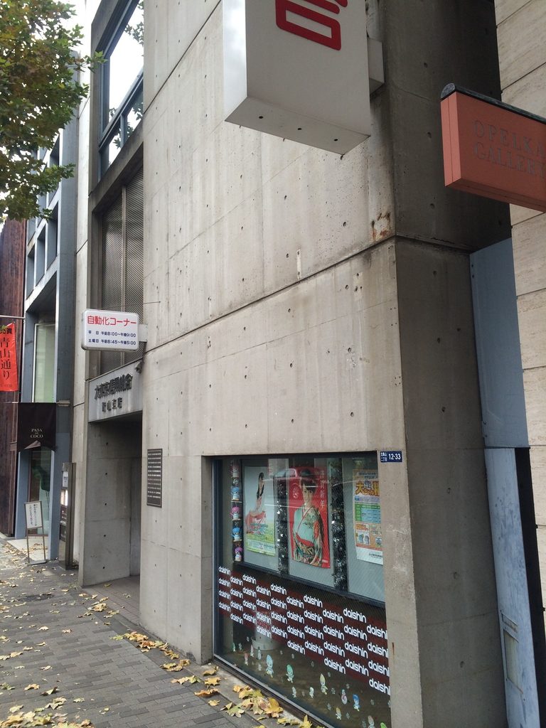 近接して見る青山TOの打放しコンクリート壁と現在の店舗設備 / Exposed-concrete wall of Aoyama TO with elements of its current use seen at close range
