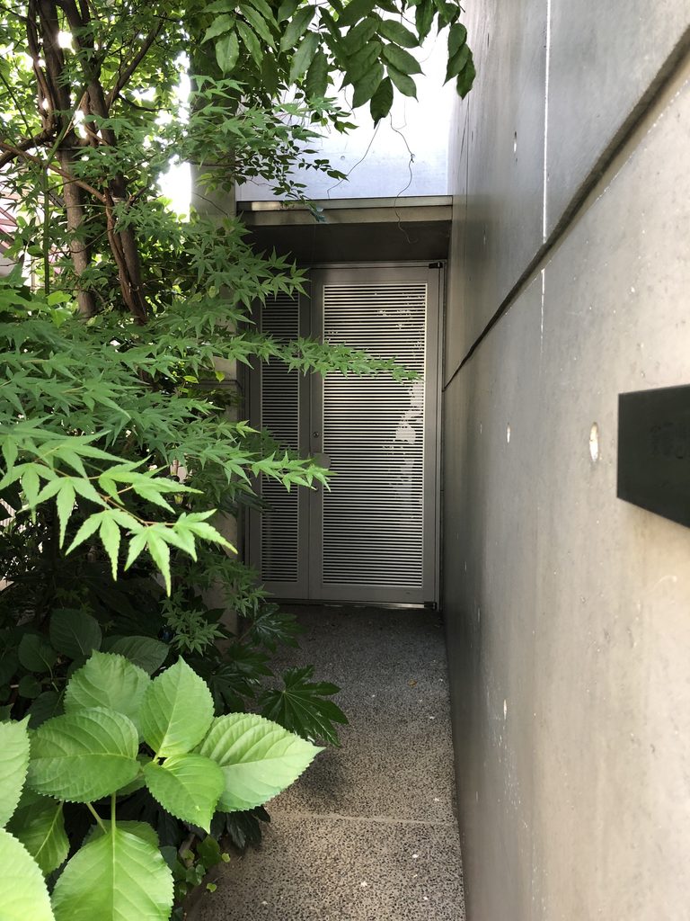 打放しの壁と植栽の間を進む入口へのアプローチ / Approach to the entrance between an exposed-concrete wall and planting