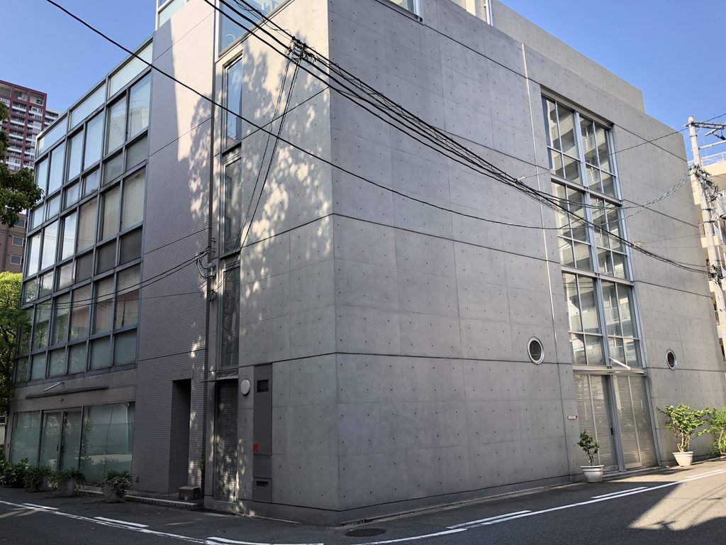 角から見たガラスの格子面と打放しコンクリートの壁 / Glass-grid elevation and exposed-concrete wall seen from the corner