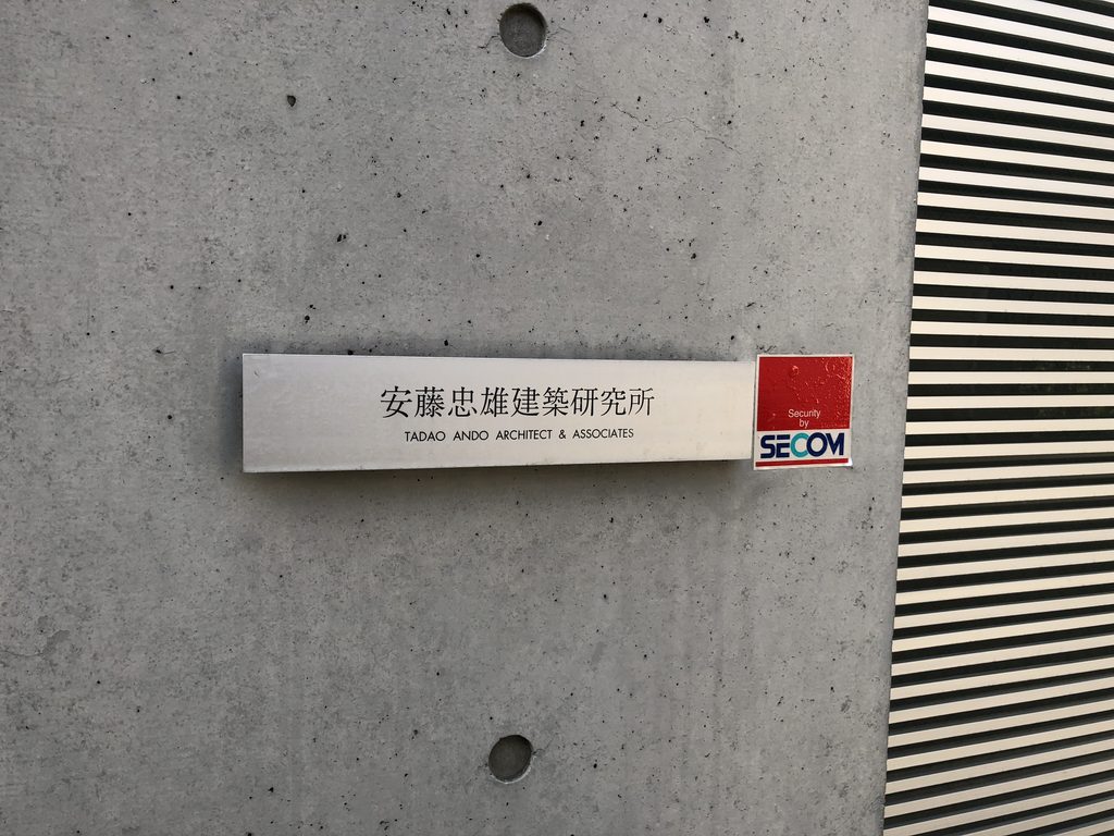 打放しの壁に掲げられた安藤忠雄建築研究所の銘板 / Tadao Ando Architect & Associates plaque on the exposed-concrete wall