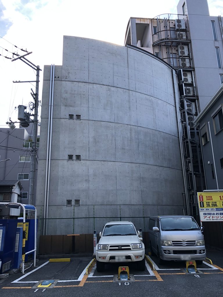 駐車場側から見た曲線を描くコンクリート壁 / Curving concrete wall of Atelier in Oyodo II seen from the parking area