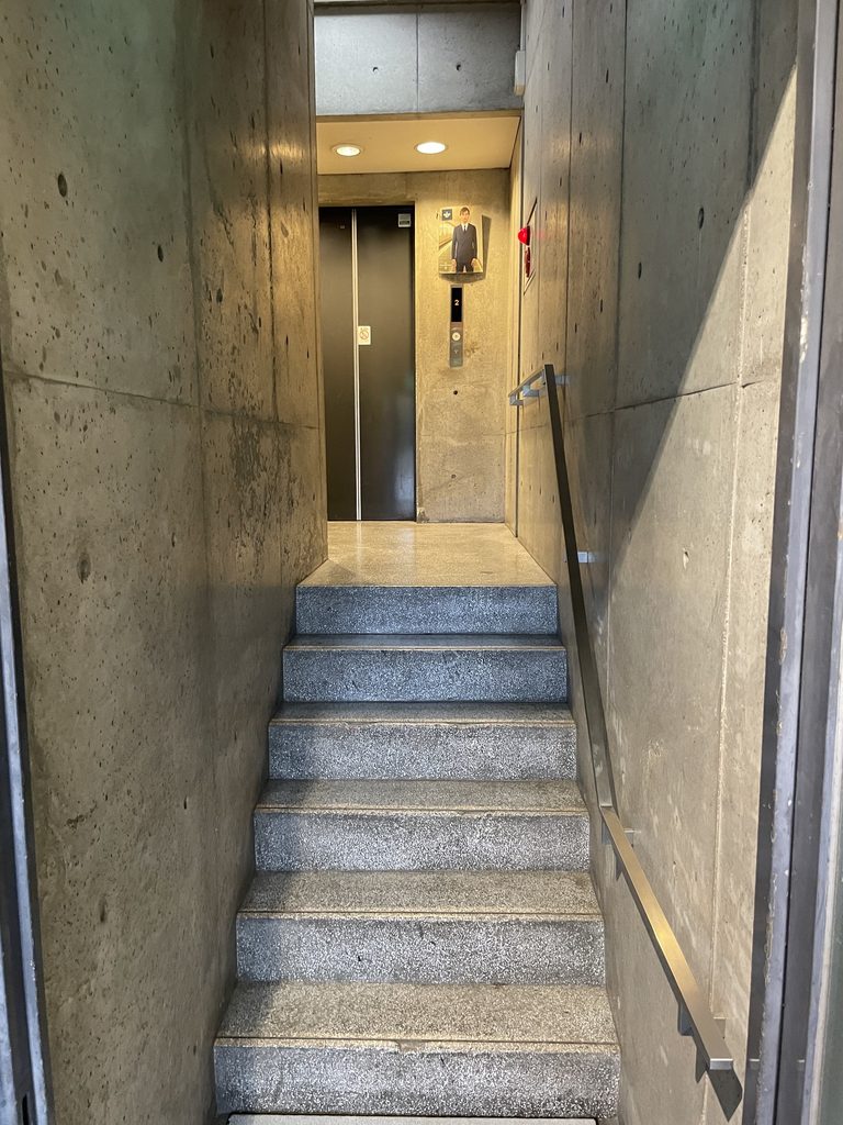 コンクリート壁に囲まれたBIGIビル内部の階段と縦方向の空間 / Stair and vertical circulation space enclosed by concrete walls inside BIGI Building