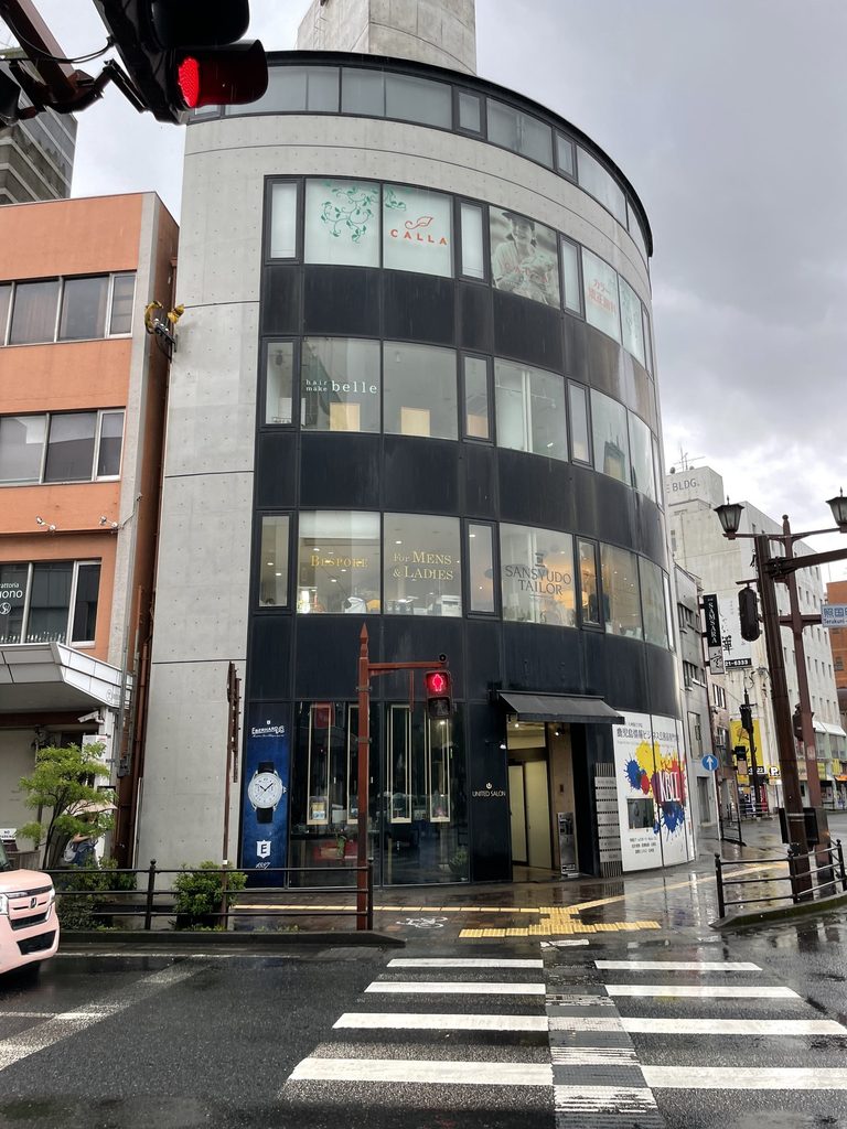 曲面に沿ってコンクリートと水平窓が積層するBIGIビル / BIGI Building with exposed concrete and horizontal windows following its curved facade