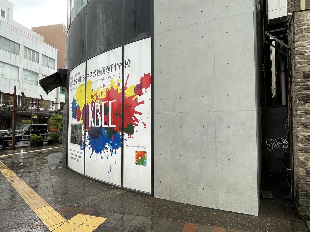 曲面ファサードから打放しコンクリート壁へ切り替わるBIGIビル側面 / Side of BIGI Building where the curved facade transitions into exposed concrete