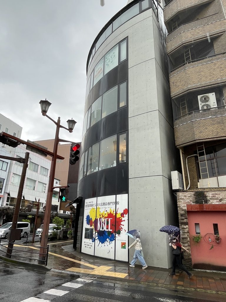 天文館の街角から斜めに見るBIGIビルの曲面外観 / Oblique street view of BIGI Building and its curved facade in Tenmonkan