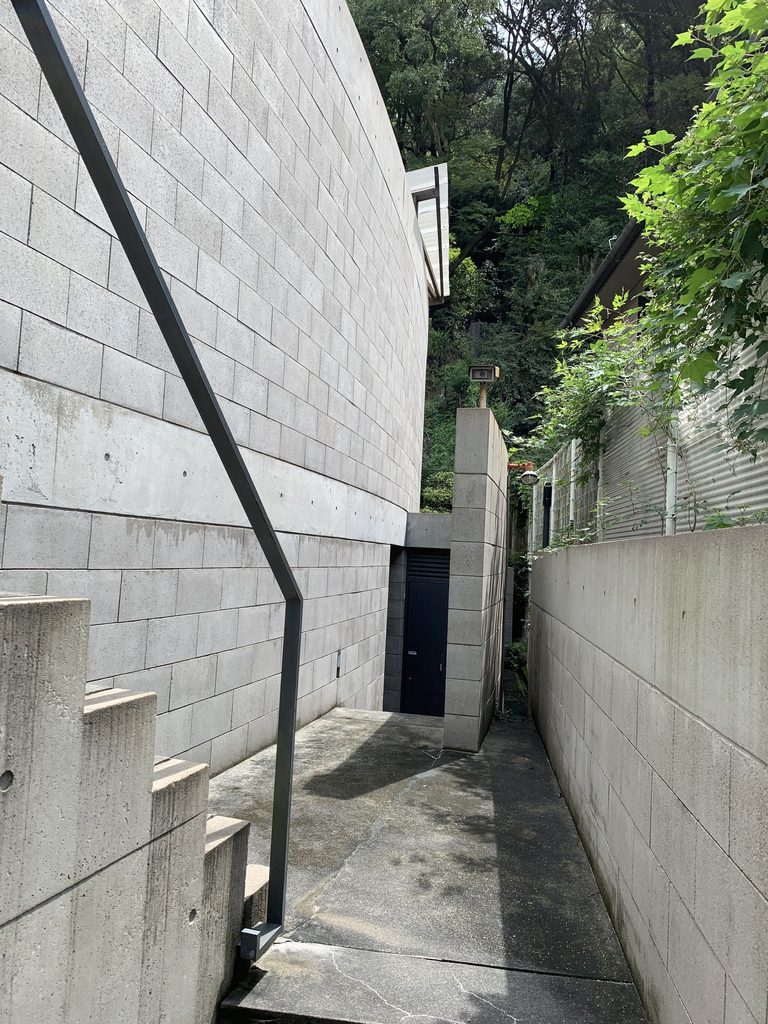 外壁の隙間から奥へ続くB-LOCK神楽岡の細い通路 / Narrow passage leading between the walls of B-LOCK Kaguraoka