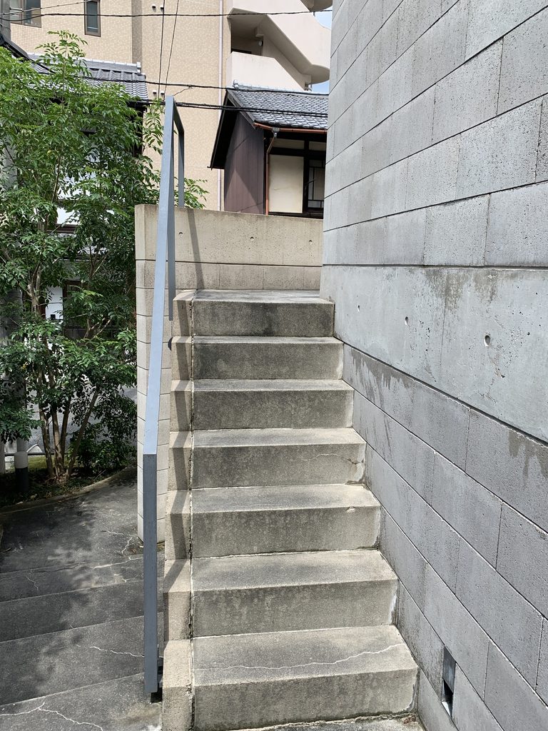コンクリートブロック壁に沿って上階へ続くB-LOCK神楽岡の階段 / Stair rising alongside concrete-block walls at B-LOCK Kaguraoka