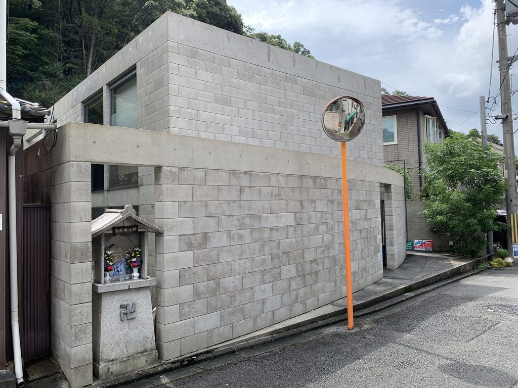 小さな地蔵と隣り合うB-LOCK神楽岡の街角外観 / Corner view of B-LOCK Kaguraoka beside a small roadside Jizo shrine