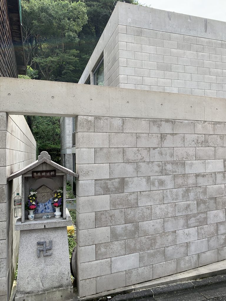 地蔵とコンクリートブロックの壁が近接するB-LOCK神楽岡の角部 / Corner of B-LOCK Kaguraoka where the concrete-block wall stands beside a roadside shrine