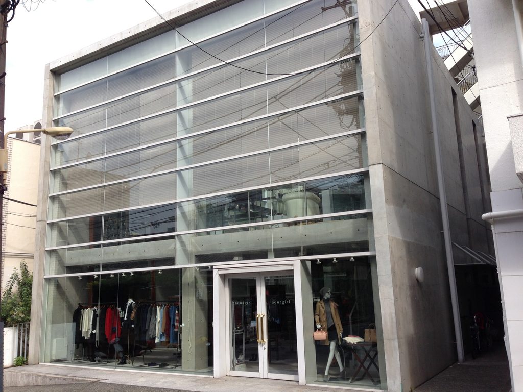 代官山の細い街路から見るCOCUEのガラス張りの正面外観 / Glazed front elevation of COCUE viewed from a narrow street in Daikanyama