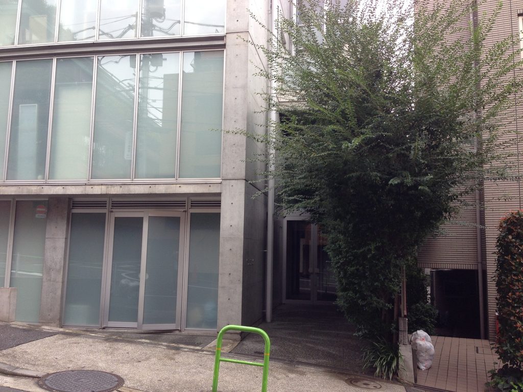 ガラス立面の脇に樹木が立つCUE NISHIAZABU低層部 / Lower portion of CUE NISHIAZABU with trees beside the glazed facade