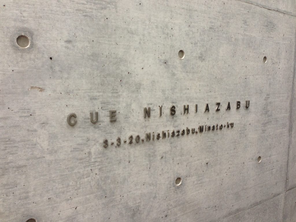 打放しコンクリート壁に記されたCUE NISHIAZABUのサイン / CUE NISHIAZABU lettering on an exposed-concrete wall