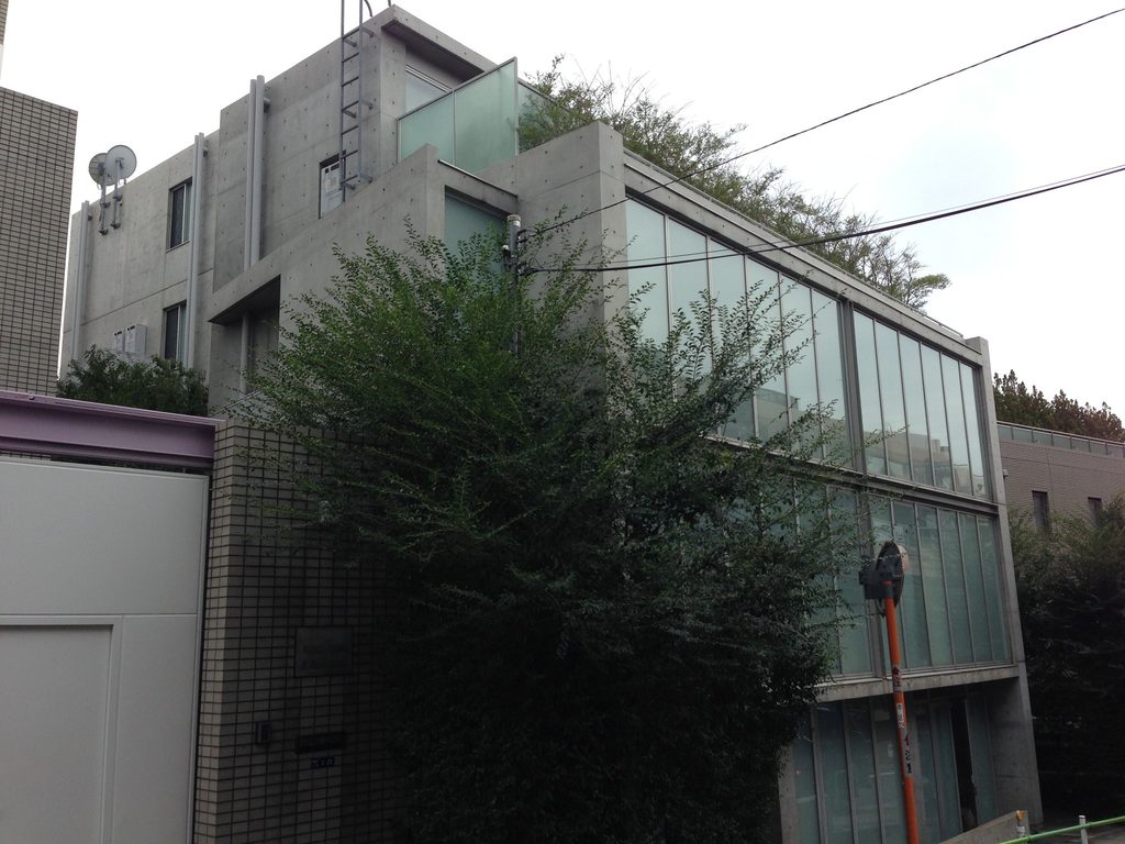 坂道から見るCUE NISHIAZABUのコンクリートとガラスの外観 / Concrete and glazed exterior of CUE NISHIAZABU viewed from the sloping street
