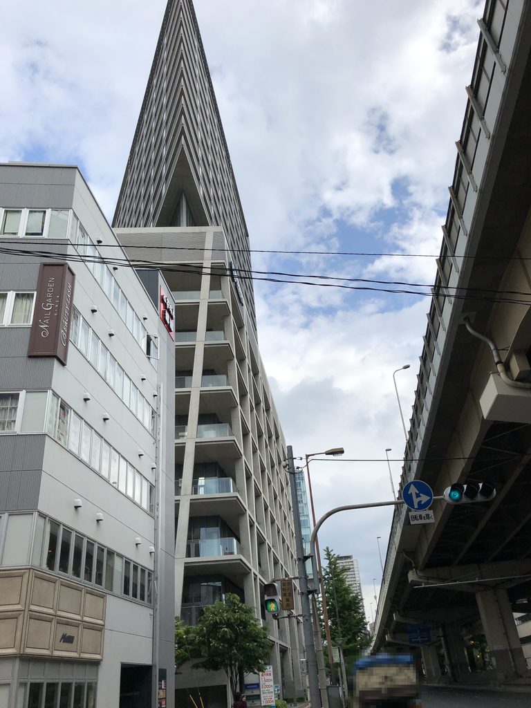 高架道路沿いから見上げた高層部の鋭角な先端 / Sharp tip of the tower seen from beside the elevated road