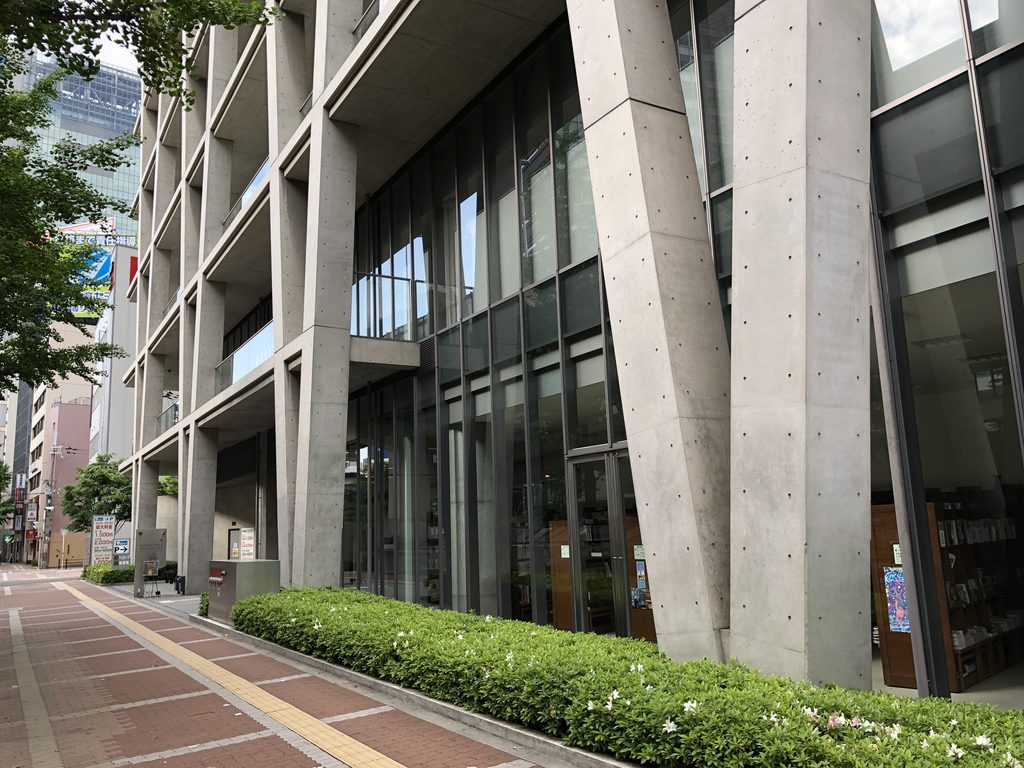 歩道沿いに立つ大きな打放しコンクリートのV字柱 / Massive exposed-concrete V-shaped columns along the sidewalk