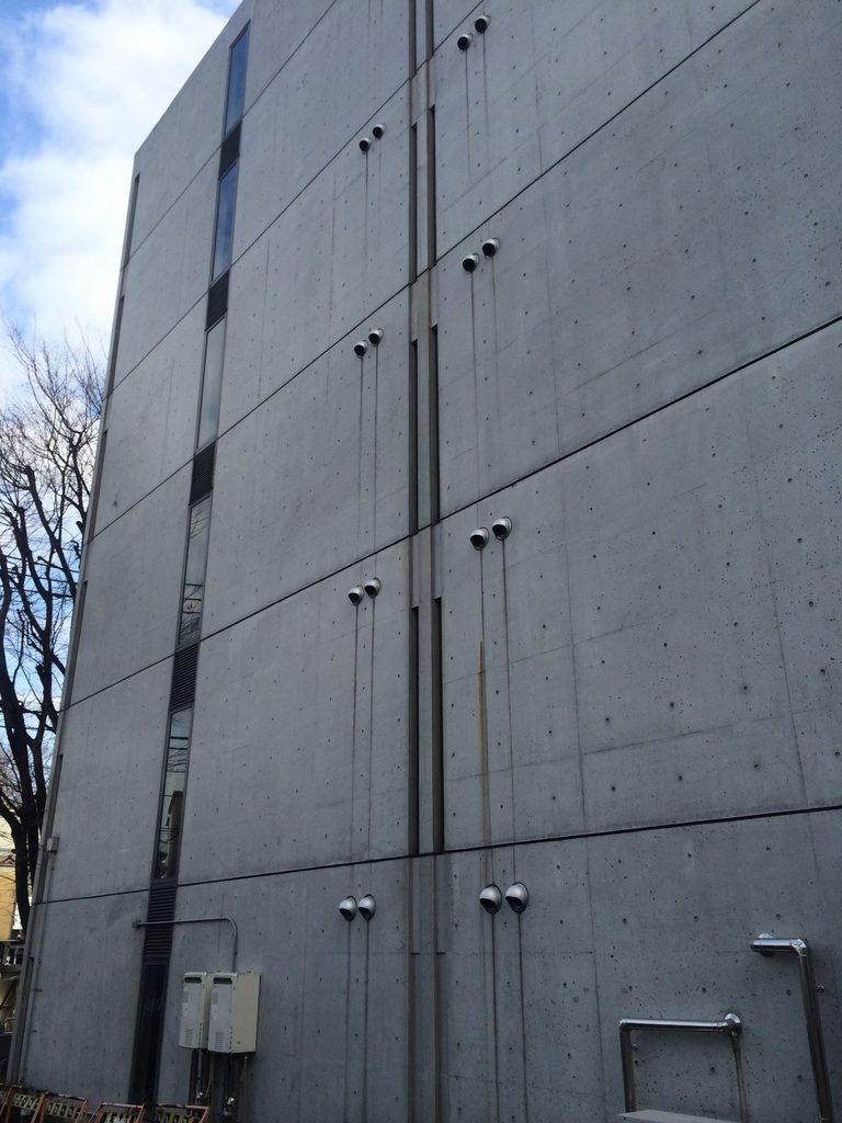 縦方向の線が刻まれた旧福原病院の打放しコンクリート側壁 / Exposed-concrete side wall of the former Fukuhara Hospital articulated by vertical lines