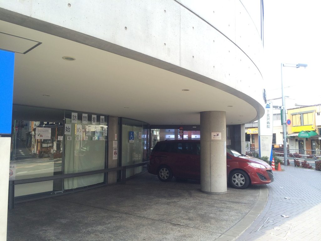 曲面庇の下に設けられた下北沢病院の車寄せと入口 / Drop-off area and entrance beneath the curved canopy of Shimokitazawa Hospital