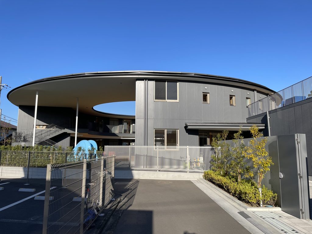 細い柱に支えられた大きな円形屋根と五風会の園舎 / Gofukai school building beneath its large circular roof supported by slender columns