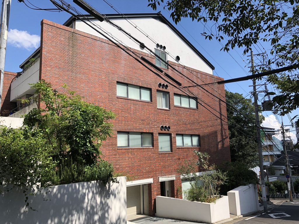坂道側から斜めに見るグランスイート北野の赤レンガ外観 / Red-brick exterior of Grand Suite Kitano viewed obliquely from the slope