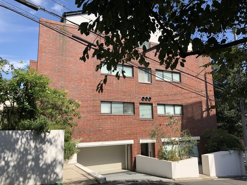 植栽と白い壁越しに見るグランスイート北野の側面 / Side elevation of Grand Suite Kitano seen beyond planting and white walls