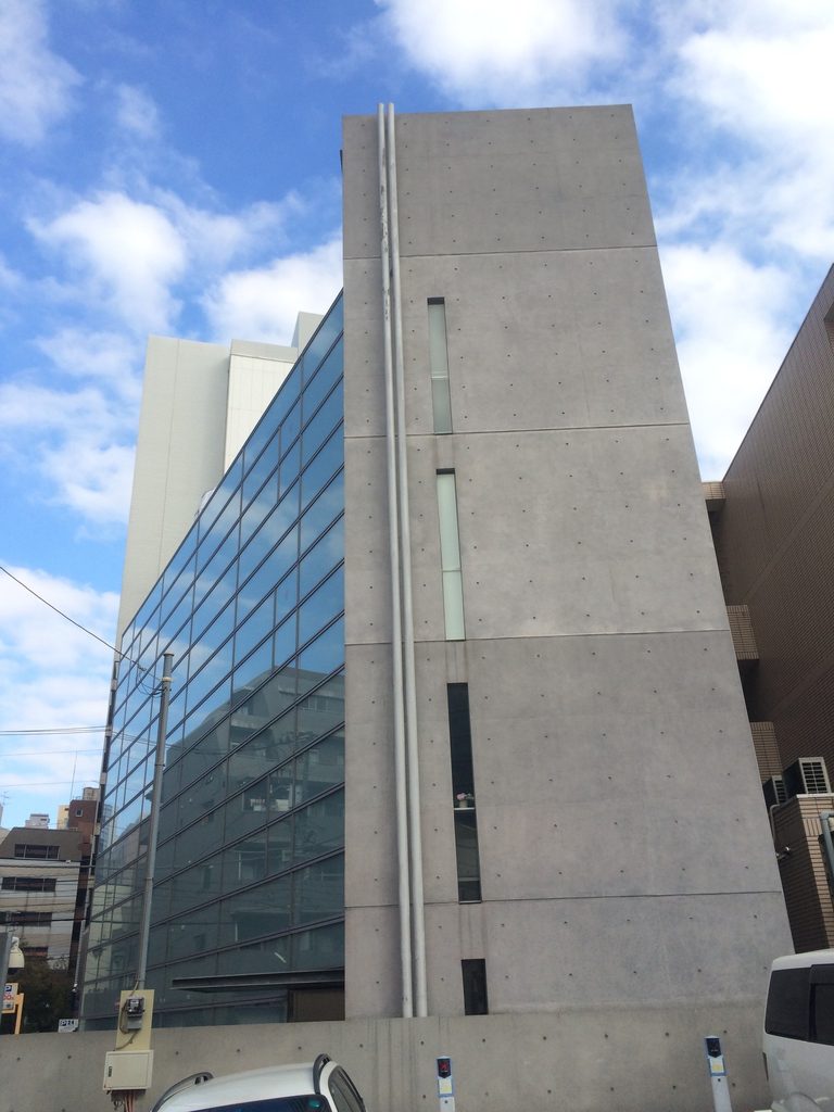縦長スリットを持つ橋本眼科西口医院の打放しコンクリート側壁 / Exposed-concrete side wall of Hashimoto Eye Clinic with narrow vertical slit windows