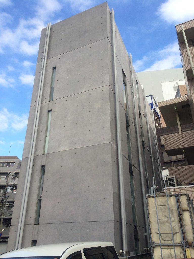 半透明ガラスと打放しコンクリートが接する橋本眼科西口医院の側面 / Side view of Hashimoto Eye Clinic where translucent glass meets exposed concrete