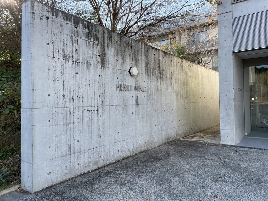 打放しコンクリート壁に刻まれたHEART WINGの文字 / HEART WING lettering on an exposed-concrete wall