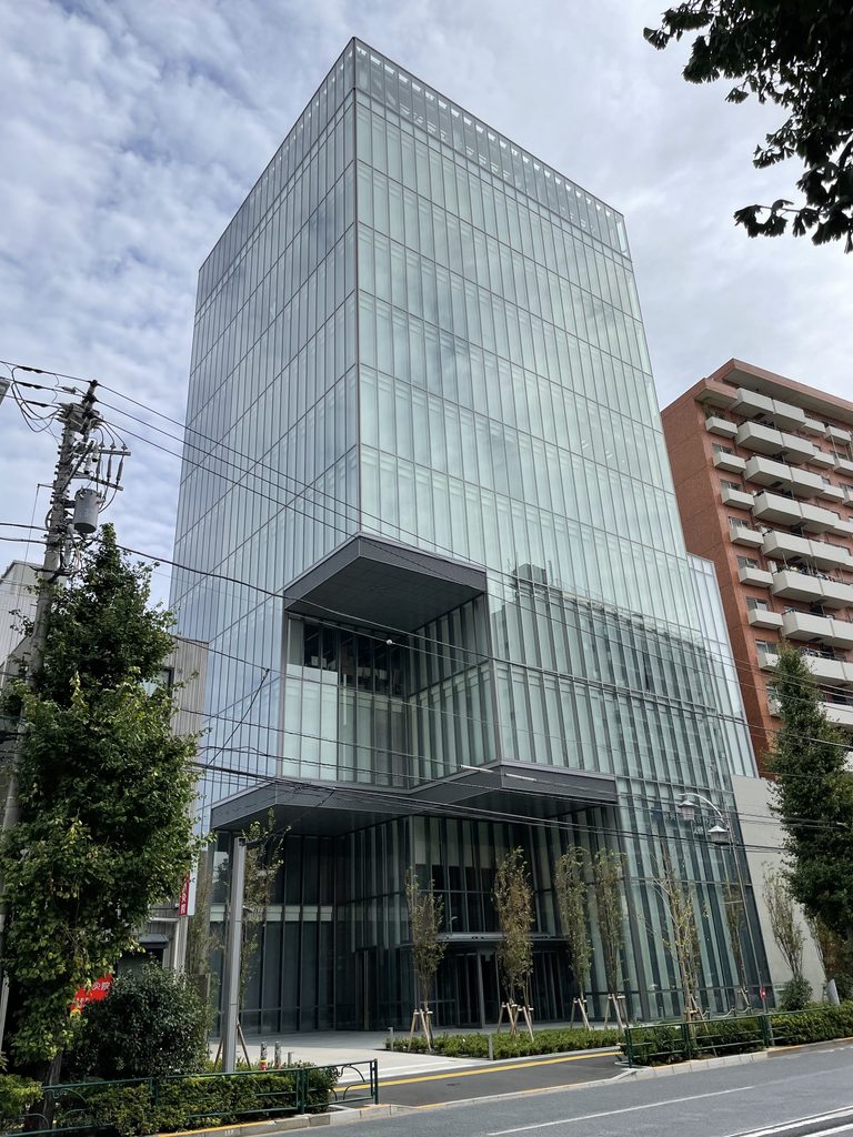 正面から見上げたガラスの塔と四層分の大きな開口 / Glass tower and four-story opening seen from below