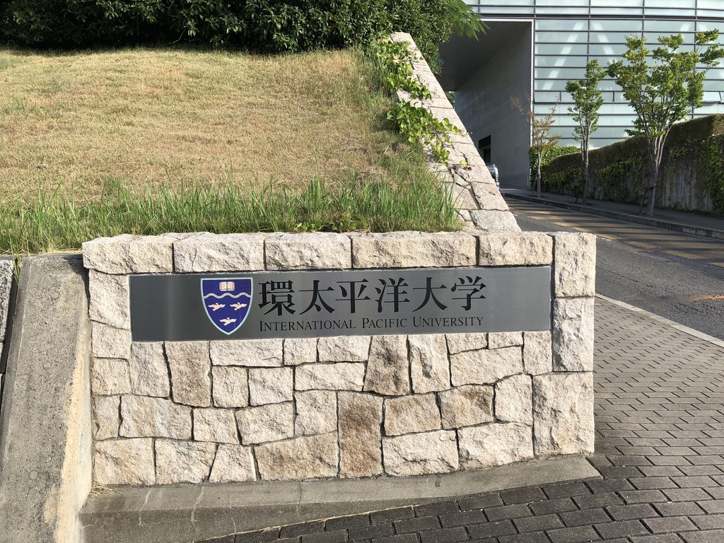 石積みの台座にはめ込まれた環太平洋大学の銘板 / IPU name plate set into a stone masonry base