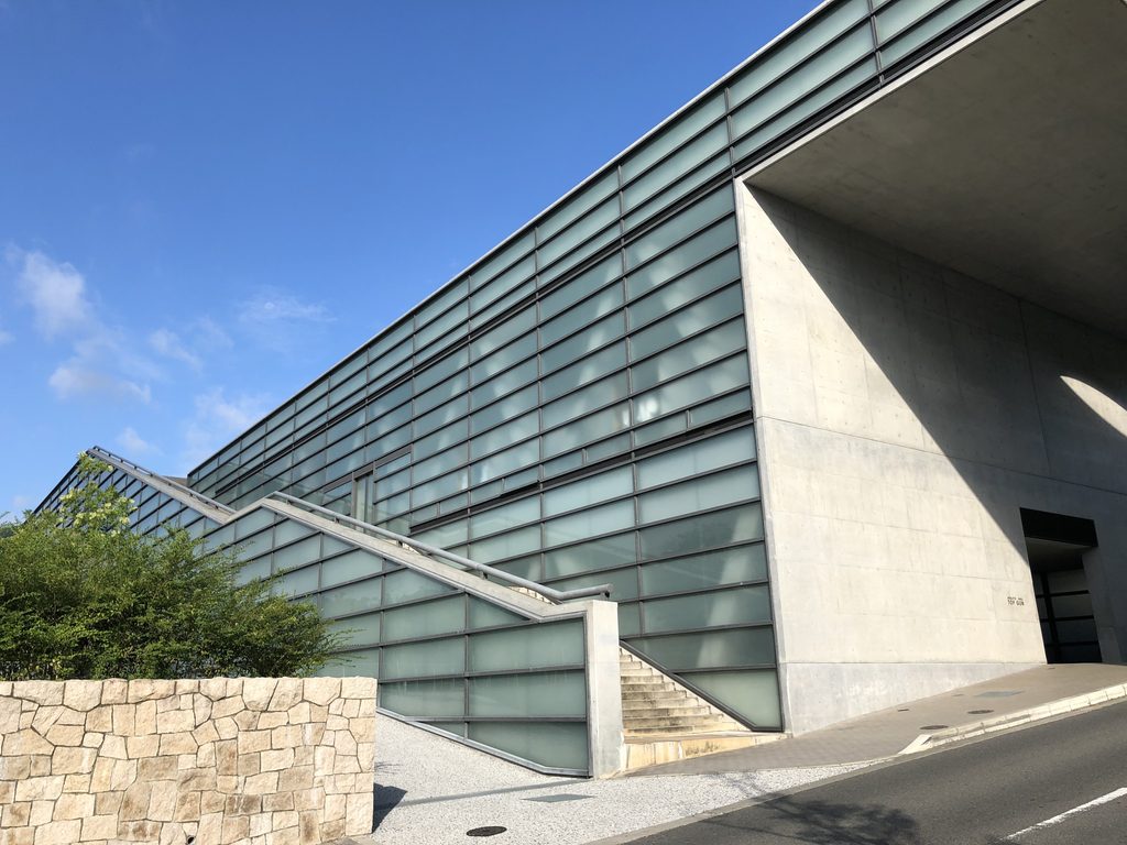 ガラスと打放しコンクリート、石積みが重なるTOPGUN側面 / Side of TOPGUN combining glass, exposed concrete and stone masonry