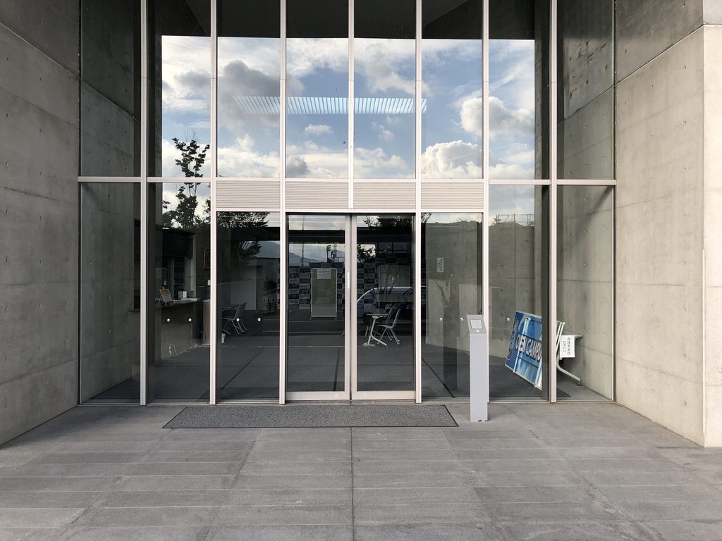 コンクリート壁に挟まれたガラスのエントランス / Glazed entrance framed by exposed-concrete walls