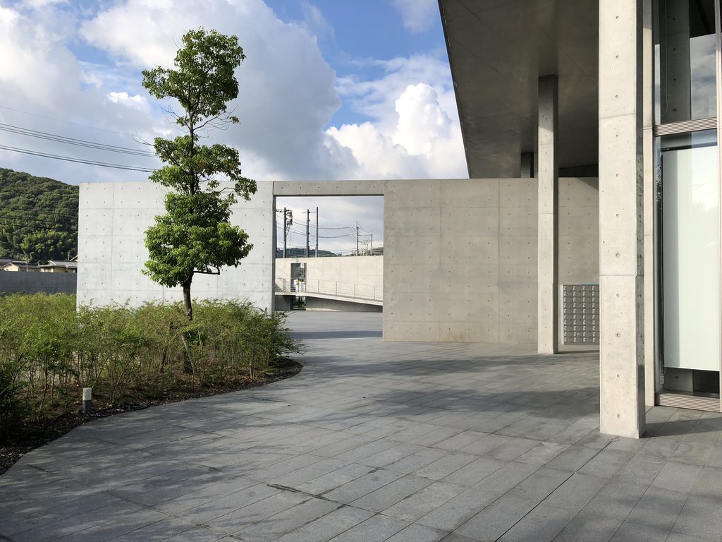 広場の端に立つ開口を持った独立壁 / Freestanding wall with an opening at the edge of the plaza