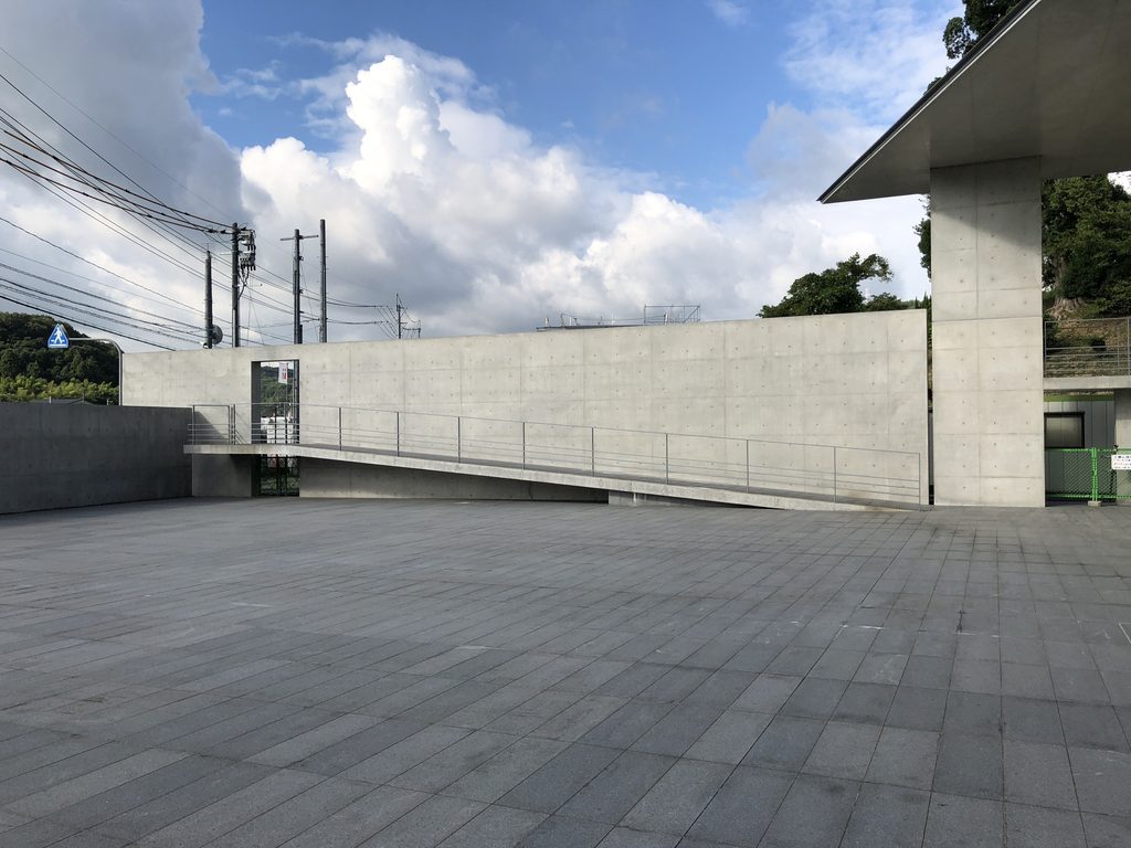 石張りの広場と道路側を仕切るコンクリート壁 / Stone-paved plaza and concrete wall separating it from the road