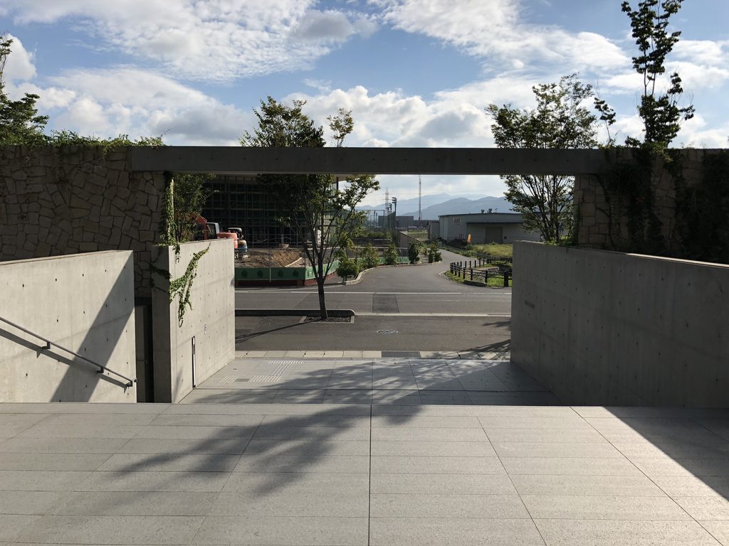 石積みの壁とコンクリート梁の向こうに見える山並み / Mountains framed beyond stone walls and a concrete beam
