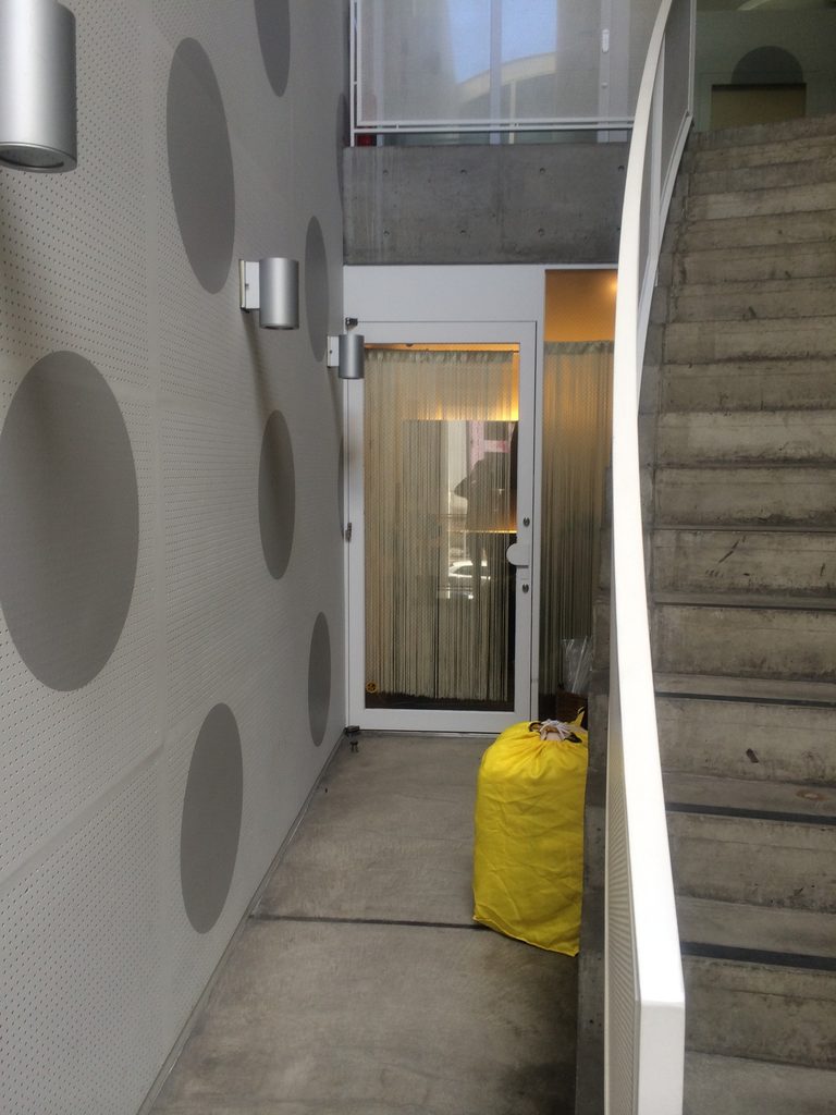 J ROOM内部で階段と店舗入口が近接する共用空間 / Shared space inside J ROOM where stairs and tenant entrances meet