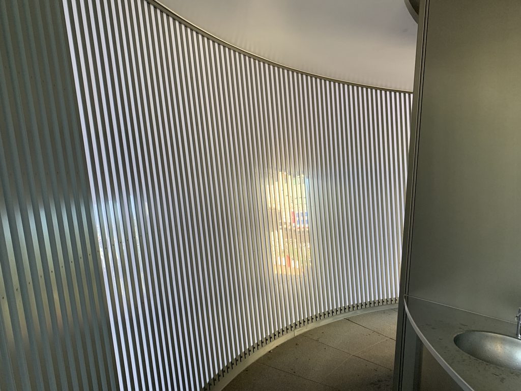 格子越しに光が入る円弧状の通路と手洗い / Curved passage and washbasin lit through the vertical lattice