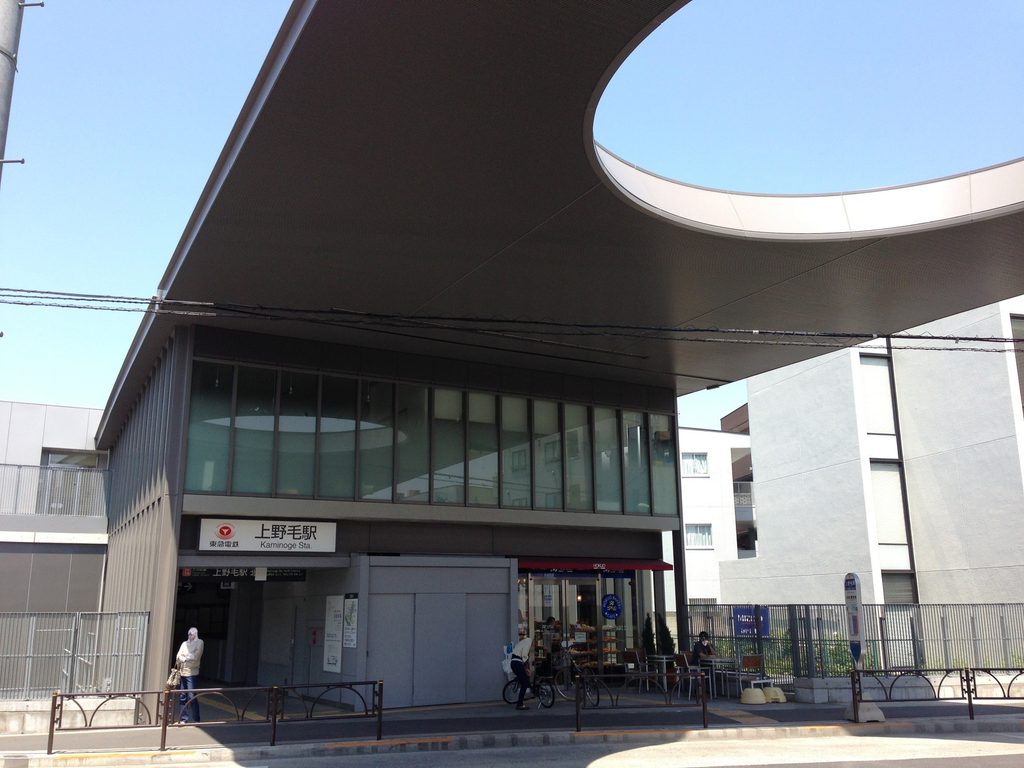 道路と駅入口を覆う大屋根と円形開口を斜めから見る上野毛駅 / Oblique view of Kaminoge Station's broad roof and circular opening above the street