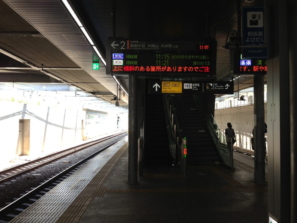 線路沿いに続く打放しコンクリート壁と上部から差す光 / Exposed-concrete wall beside the tracks illuminated by daylight from above