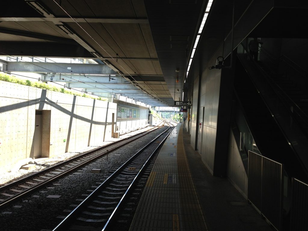 打放しコンクリート壁の間をホームへ下りる階段 / Stairs descending toward the platform between exposed-concrete walls