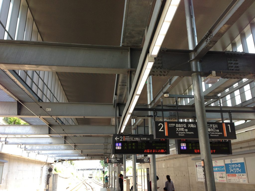 掘割状の線路とコンクリート壁、鉄骨屋根が続く上野毛駅ホーム / Kaminoge Station platform with tracks in a cutting, concrete walls and steel roof structure