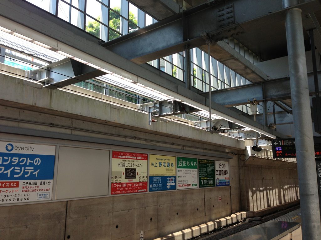 ホームから見上げた鉄骨梁とガラス面、その向こうに見える空 / Steel beams and glazing seen from the platform with sky visible beyond
