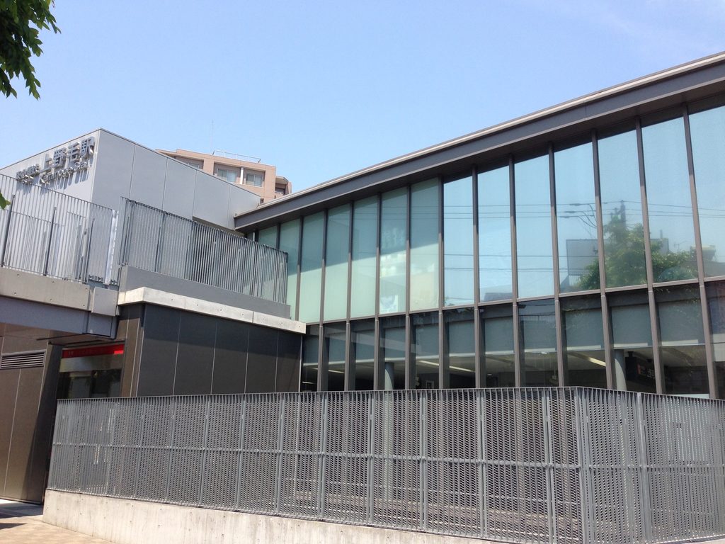 低く長いガラス壁と大屋根が並行して伸びる上野毛駅外観 / Exterior of Kaminoge Station with its long glazed wall beneath the broad roof