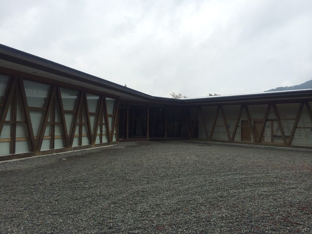 木造の低層棟に囲まれた加子母村ふれあいコミュニティセンターの中庭状空間 / Courtyard-like exterior space enclosed by low timber wings at Kashimo-Mura Community Center