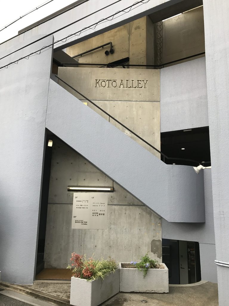 甲東アレイの打放しコンクリート壁に刻まれた建物名と外部階段 / KOTO ALLEY lettering and exterior stair set against the exposed-concrete wall