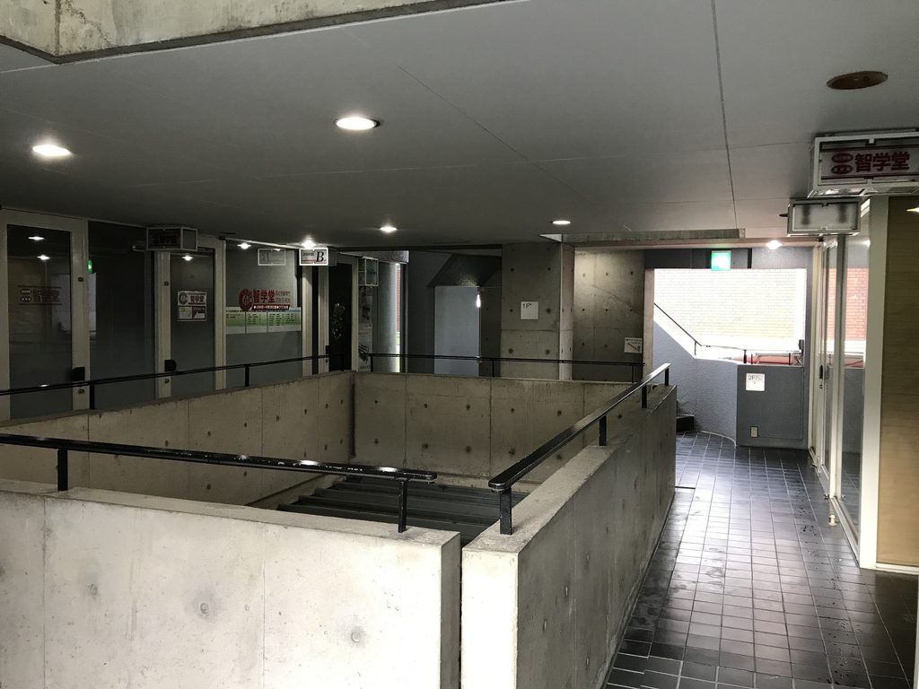 甲東アレイ内部の吹抜けを囲む打放しコンクリートの腰壁と通路 / Exposed-concrete parapets and circulation surrounding the interior void of Koto Alley