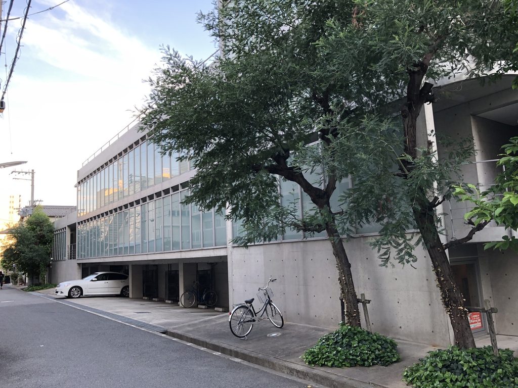 樹木越しに見たマグノリアの長いガラス張りの立面 / Long glazed elevation of MAGNOLIA seen through mature street trees