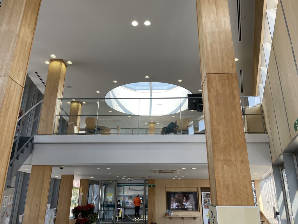 円形の天井開口と木柱が見える三河田原駅の吹き抜け空間 / Interior of Mikawa-Tahara Station with timber columns and a circular ceiling opening