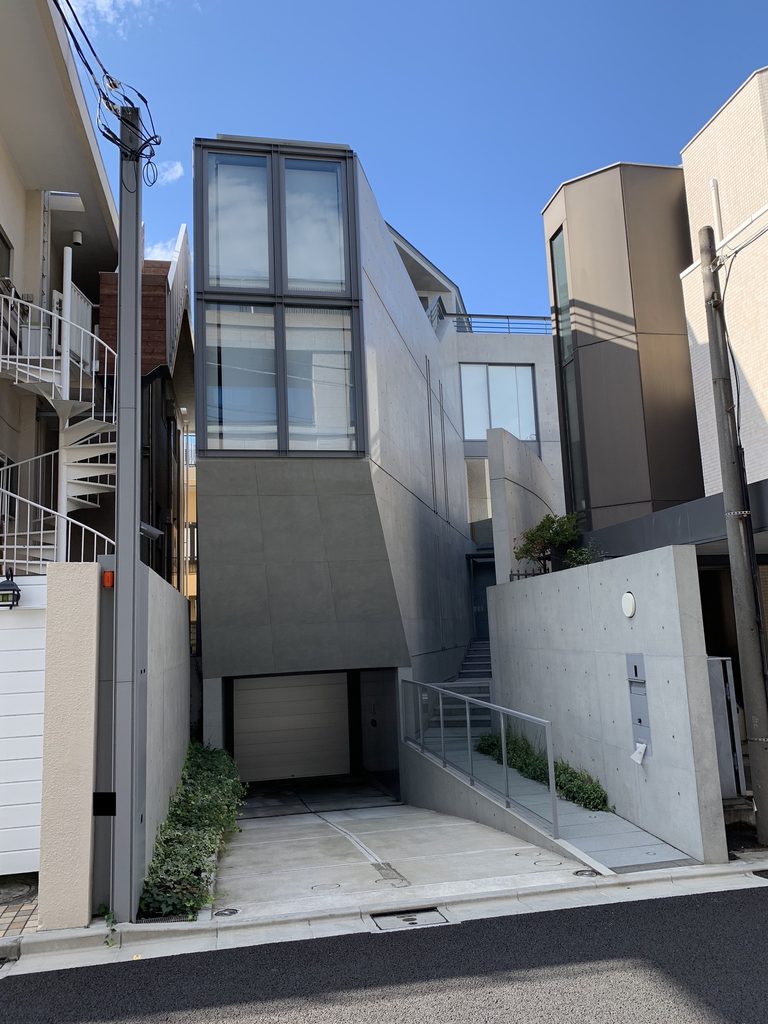 元麻布の住宅の縦長のガラス面と打放しコンクリート壁を街路から見る / Street view of the tall glazed facade and exposed-concrete walls of House in Motoazabu