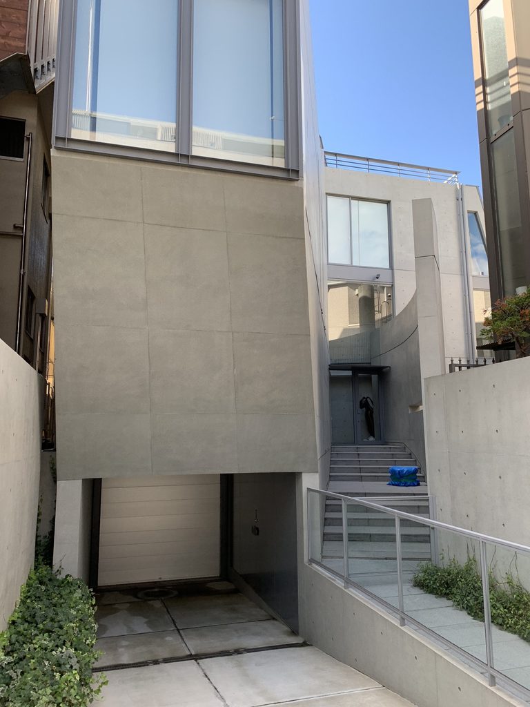 車庫の上に張り出す元麻布の住宅の斜めのコンクリート壁 / Angled concrete wall projecting above the garage entrance of House in Motoazabu
